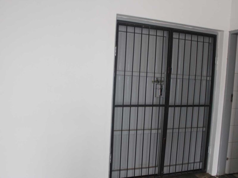 An interior entry area featuring a secure metal gate and neutral wall finishes, providing a clean and functional access point.