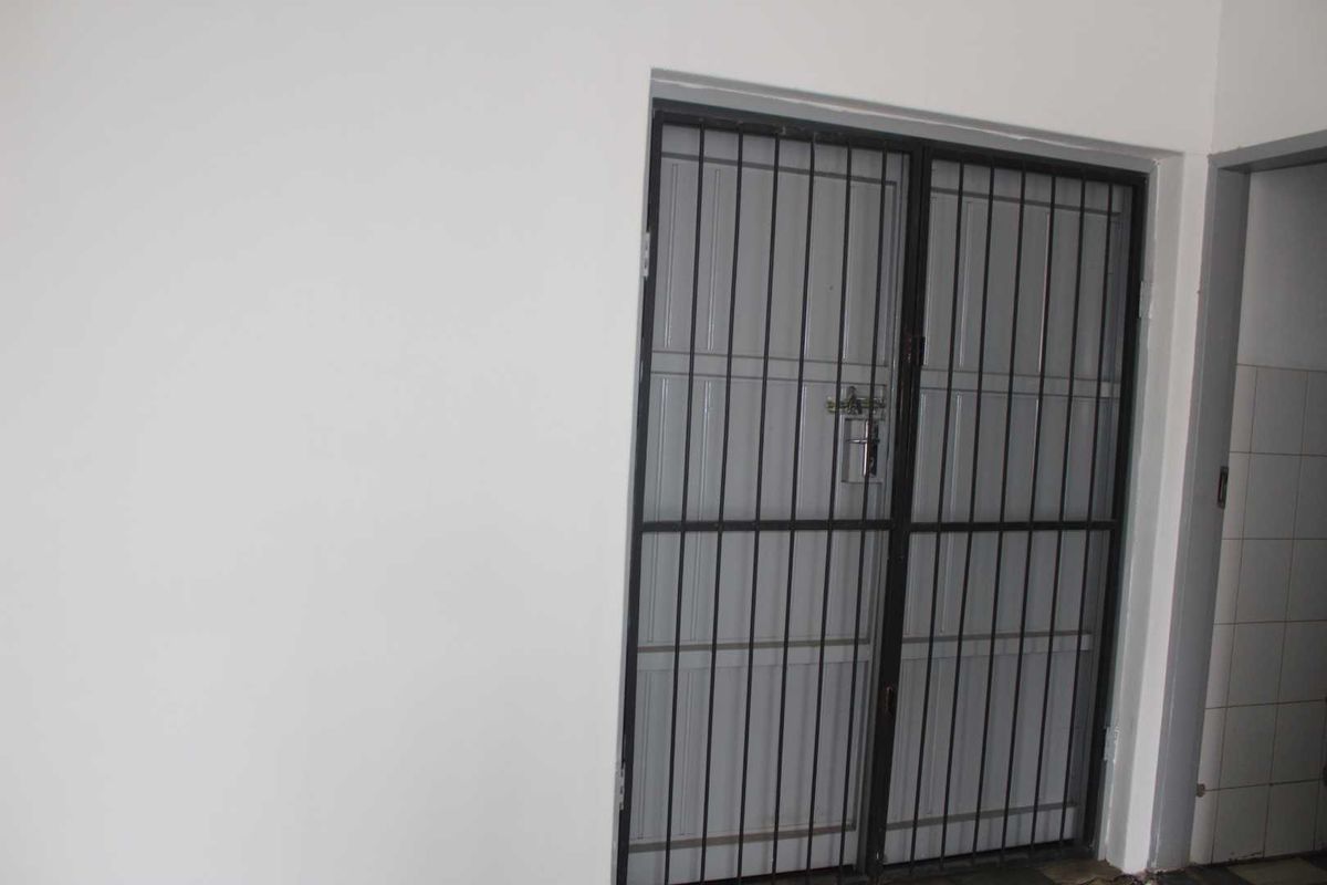 An interior entry area featuring a secure metal gate and neutral wall finishes, providing a clean and functional access point.