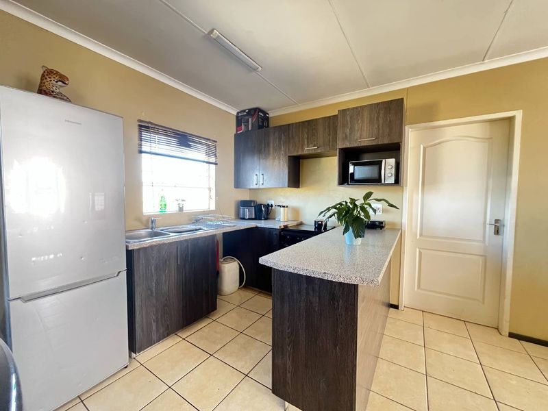 A functional kitchen featuring dark wood-look cabinetry, laminate countertops, ceramic floor tiles, and a built-in microwave space.