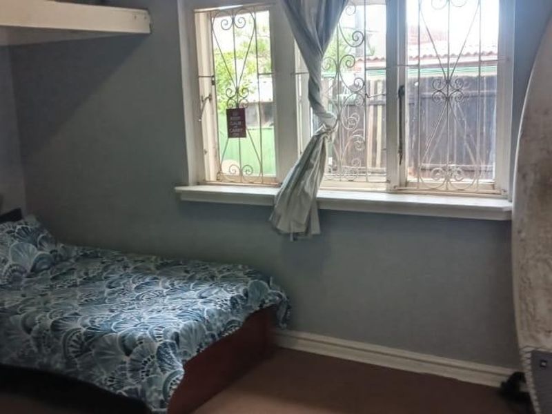 A bedroom featuring a built-in bunk bed frame and windows fitted with security bars.