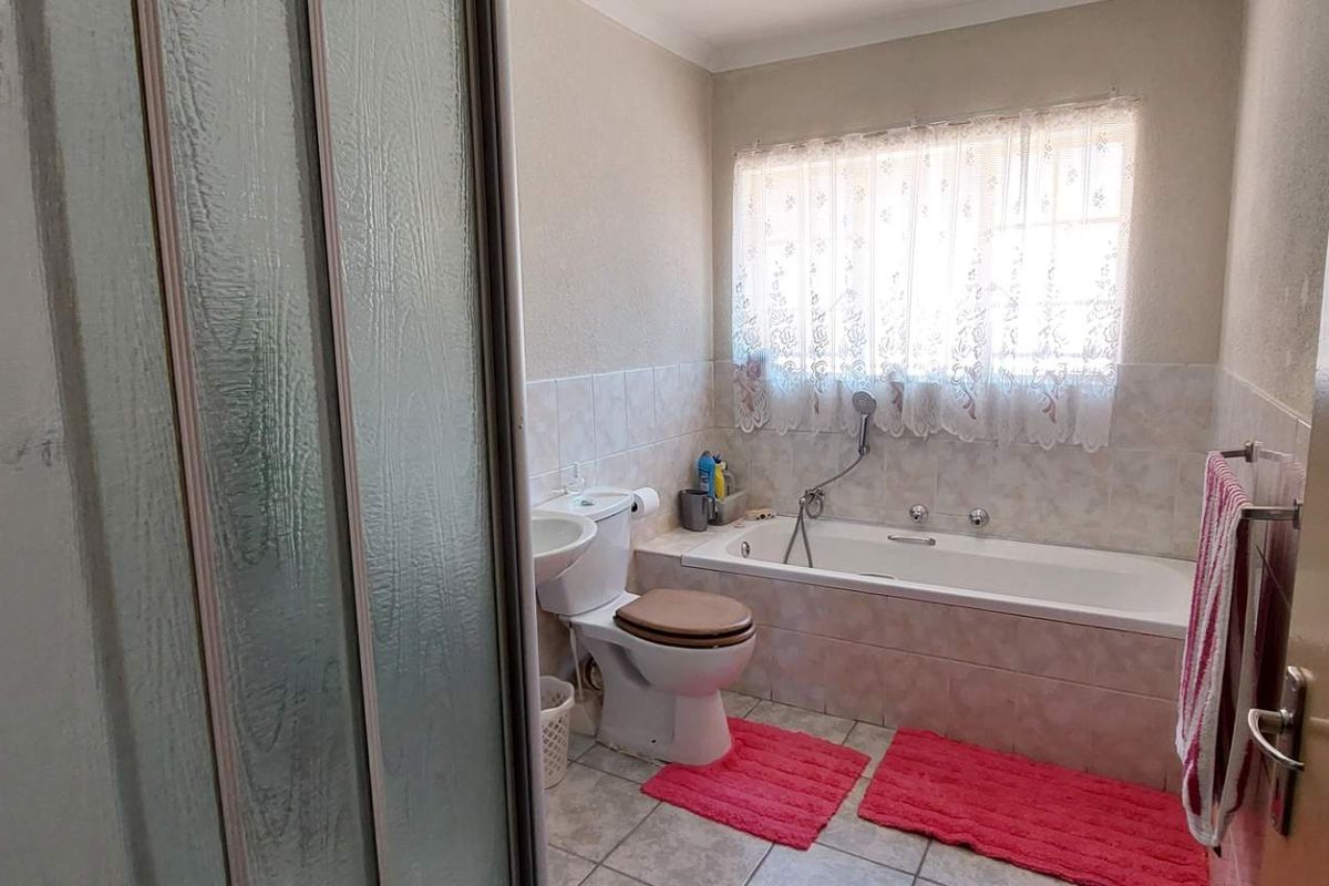 A functional bathroom featuring a built-in bathtub, a separate shower enclosure, a toilet, and a pedestal basin with tiled flooring.