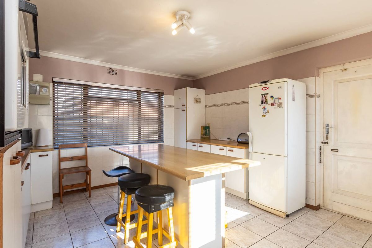 A functional kitchen featuring tiled flooring, a central island with breakfast bar seating, built-in cabinetry, and a tiled backsplash.