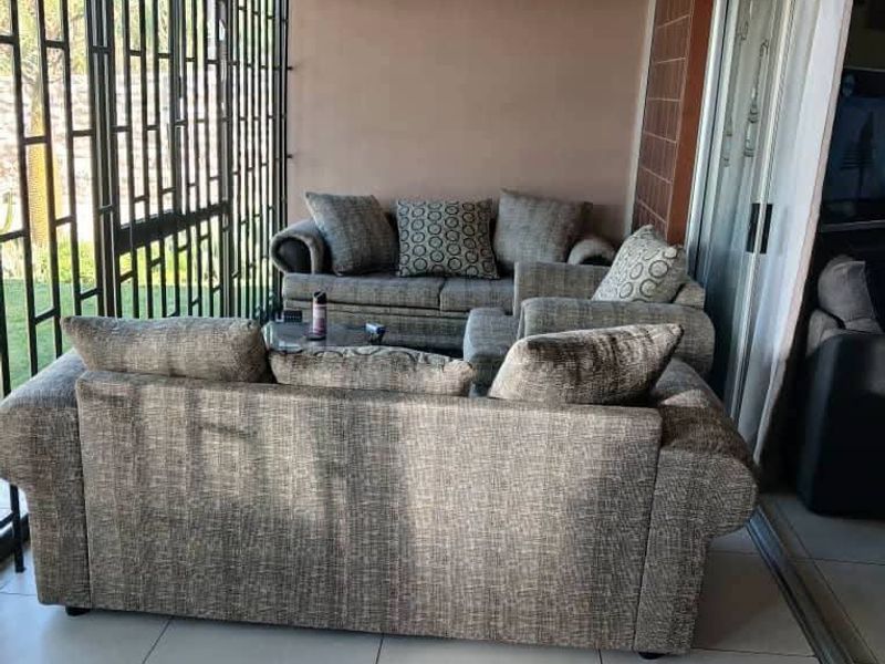 A covered patio area featuring tiled flooring, security gates, and sliding glass doors providing access to the main living space.