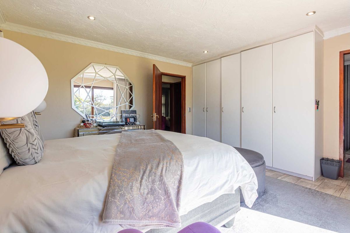 A well-maintained bedroom featuring extensive built-in cupboards, recessed downlighting, and neutral tiled flooring.