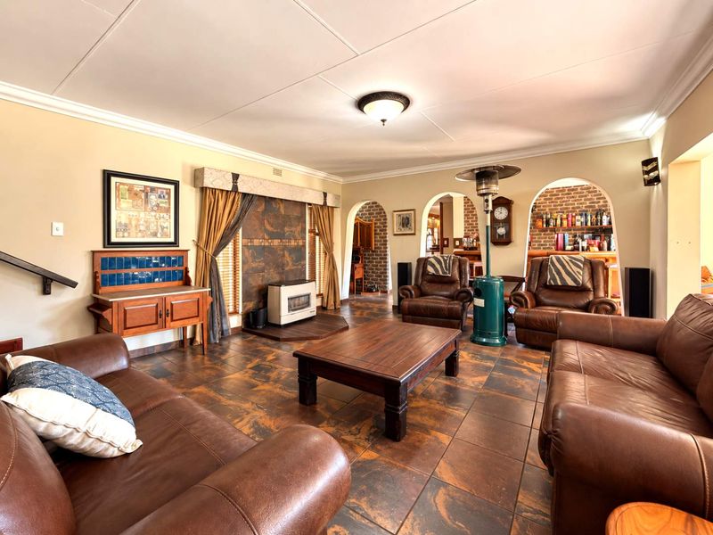 Spacious living room featuring tiled flooring, arched doorways leading to adjacent areas, and a built-in fireplace with decorative tiling.