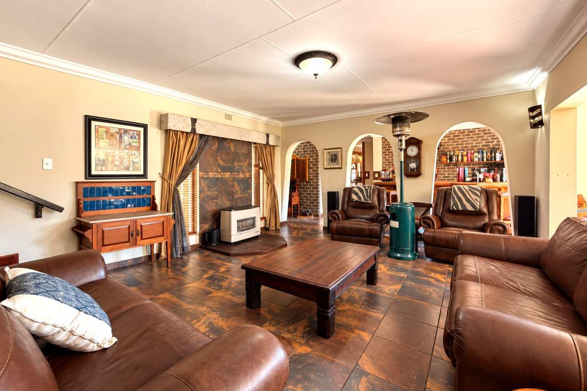 Spacious living room featuring tiled flooring, arched doorways leading to adjacent areas, and a built-in fireplace with decorative tiling.
