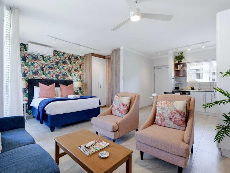 An open-plan studio apartment featuring a combined living and sleeping area with tiled floors, built-in storage, ceiling fan, and a compact kitchenette.