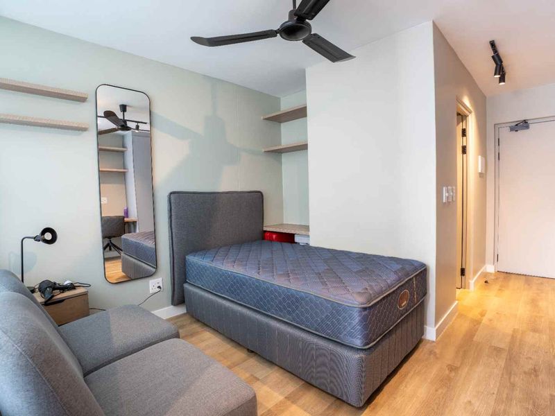 A modern, well-maintained bedroom featuring laminate flooring, a ceiling fan, and built-in shelving units.