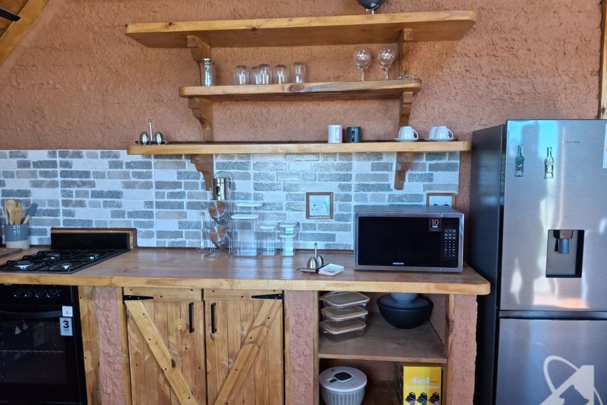 Rustic kitchen area featuring wooden cabinetry, open shelving, a tiled backsplash, and built-in cooking appliances.
