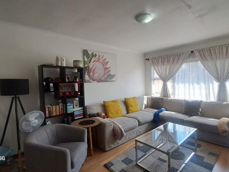 A comfortable living room featuring laminate flooring and a large sliding glass door that provides natural light.
