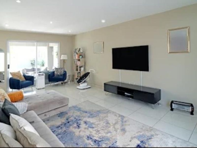 Spacious living room featuring neutral walls, tiled flooring, recessed lighting, and large sliding glass doors providing access to the patio area.