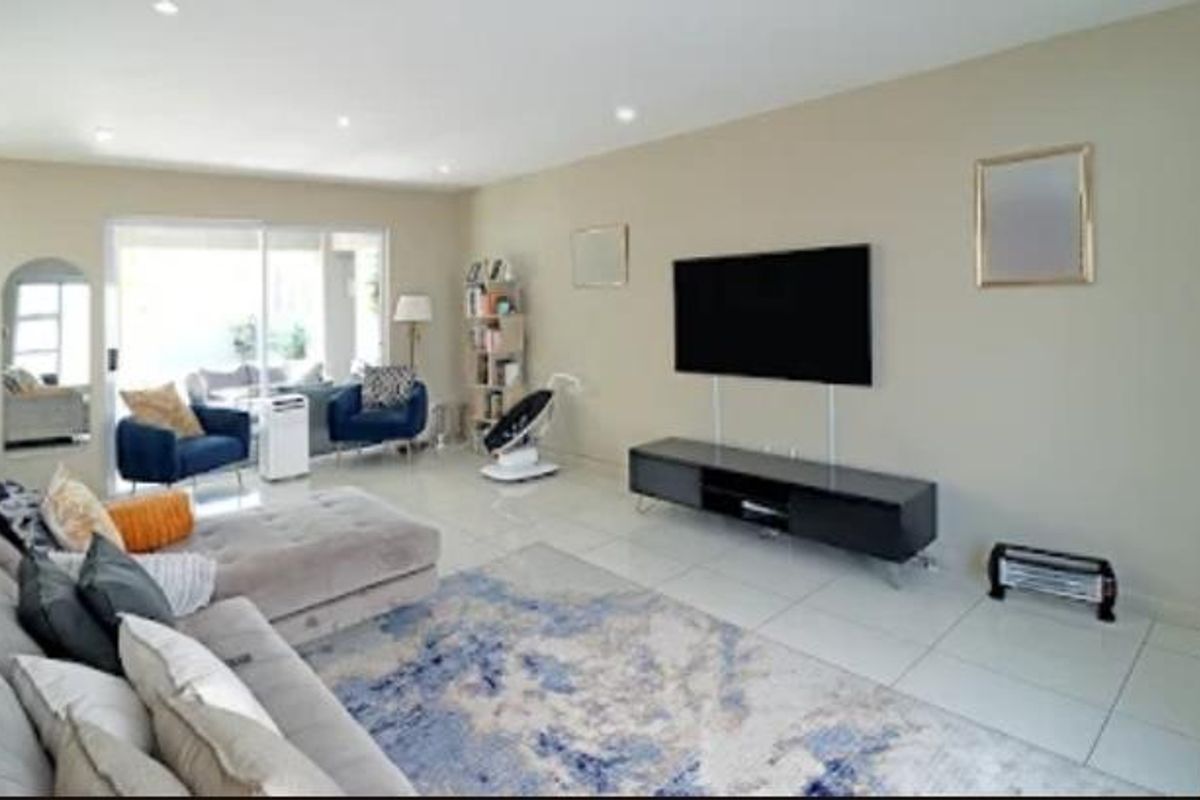 Spacious living room featuring neutral walls, tiled flooring, recessed lighting, and large sliding glass doors providing access to the patio area.