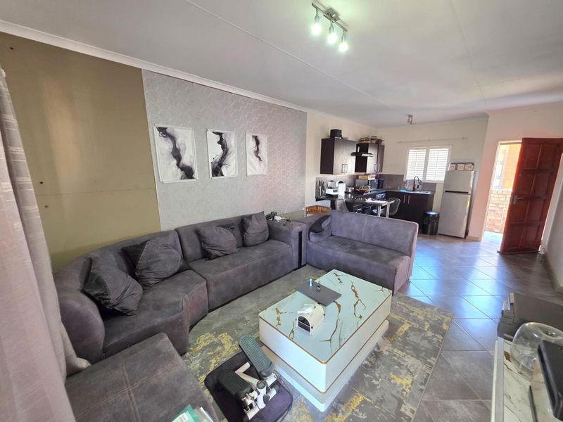Open-plan living area featuring tiled flooring and a compact kitchen with built-in cabinetry and an extractor fan.