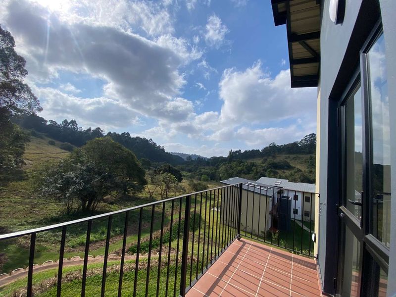 A private balcony featuring tiled flooring and a metal balustrade, offering scenic views of the surrounding landscape and estate grounds.
