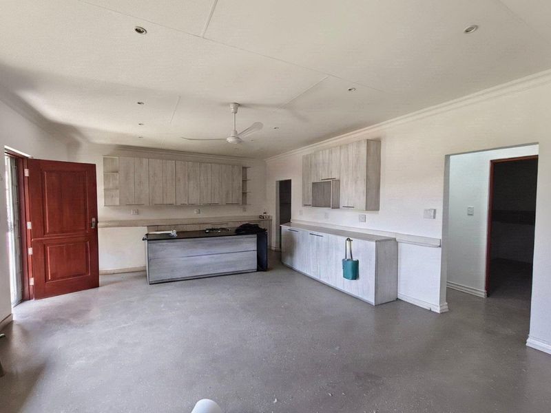 Spacious kitchen area featuring light wood-finish cabinetry, a central island, and recessed lighting, currently presented as an empty, blank canvas ready for final finishes.