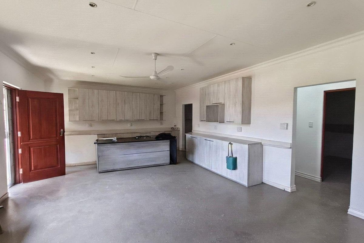 Spacious kitchen area featuring light wood-finish cabinetry, a central island, and recessed lighting, currently presented as an empty, blank canvas ready for final finishes.