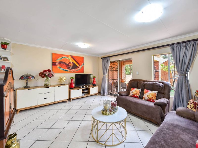 A comfortable living room featuring tiled flooring, built-in shelving, and a sliding glass door providing access to the outdoor area.
