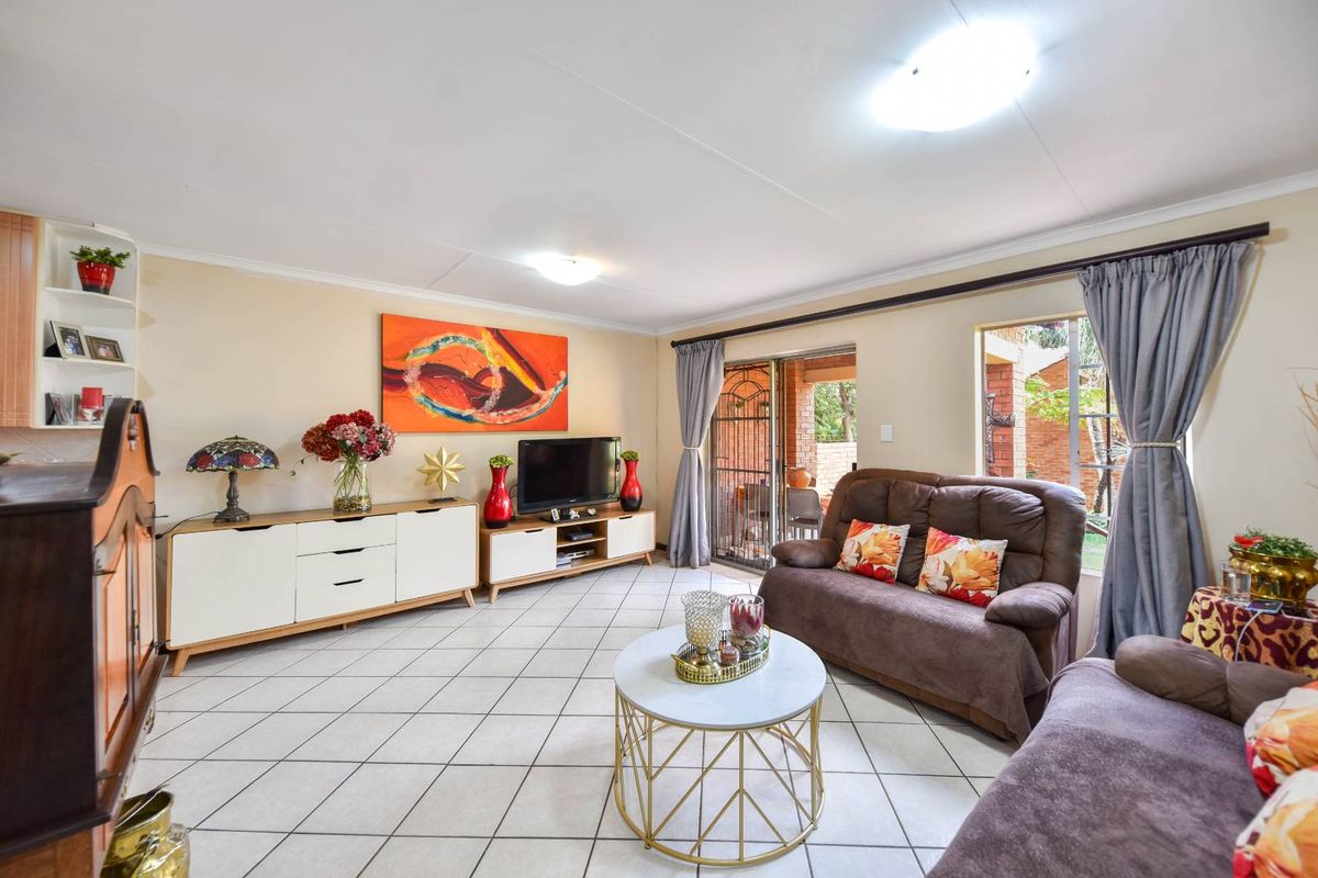 A comfortable living room featuring tiled flooring, built-in shelving, and a sliding glass door providing access to the outdoor area.