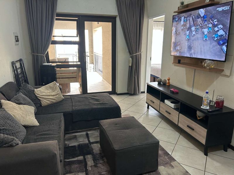 A living room featuring tiled flooring and a sliding glass door providing access to an outdoor balcony area.