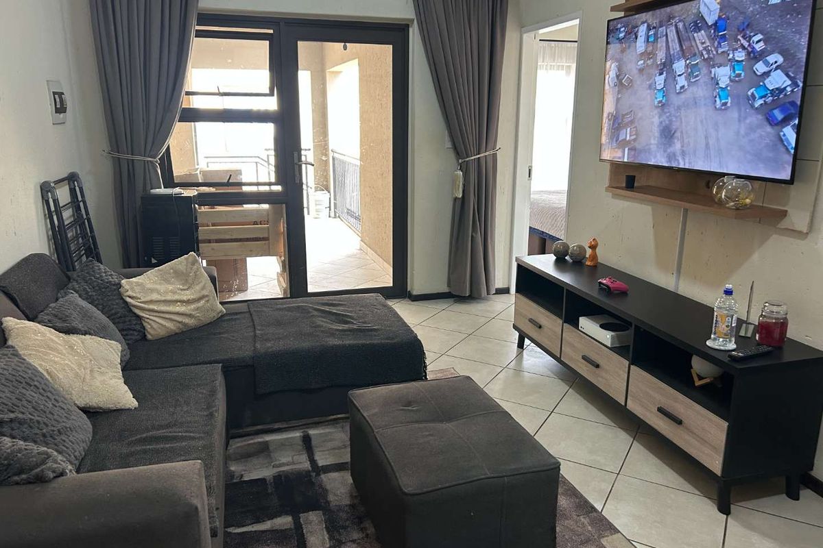 A living room featuring tiled flooring and a sliding glass door providing access to an outdoor balcony area.