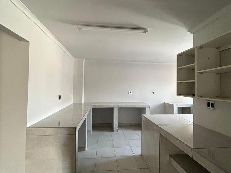 An empty, functional kitchen space featuring tiled countertops and built-in tiled cabinetry, offering a blank canvas for renovation or modernization.