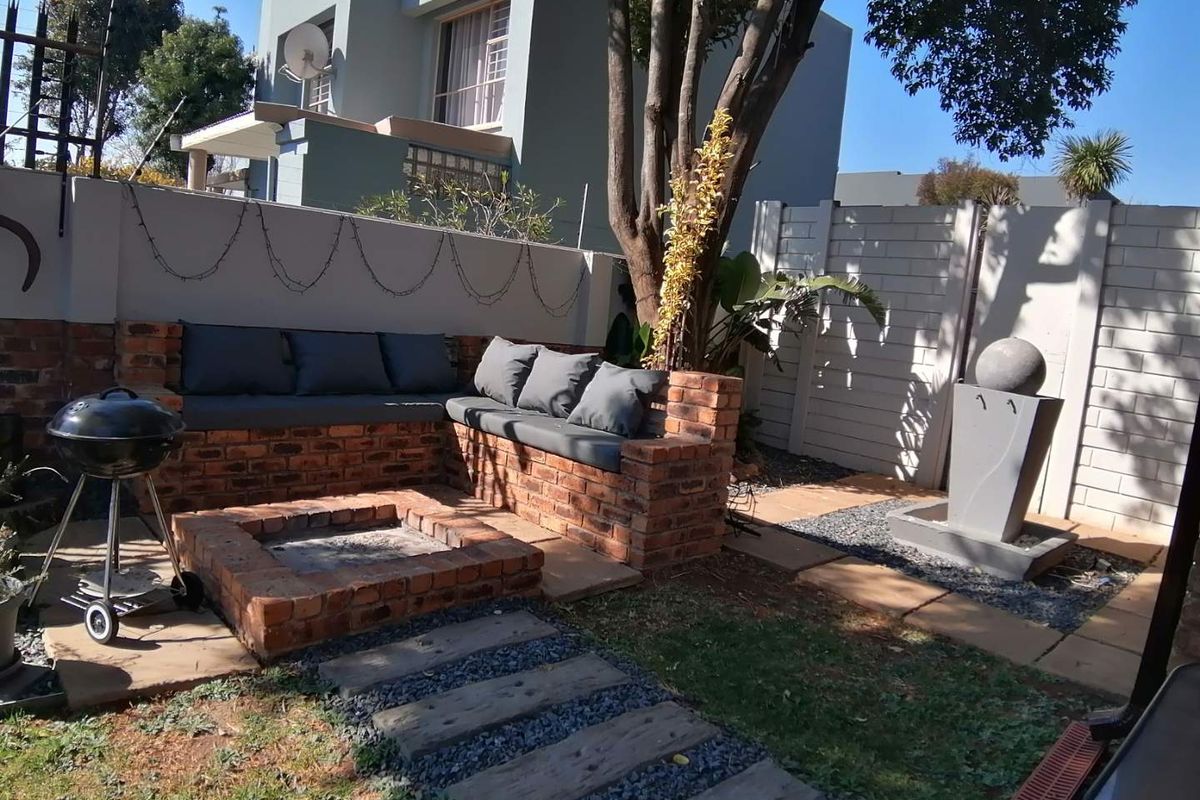 A private rear garden area featuring a built-in brick fire pit, integrated seating, and a decorative water feature.