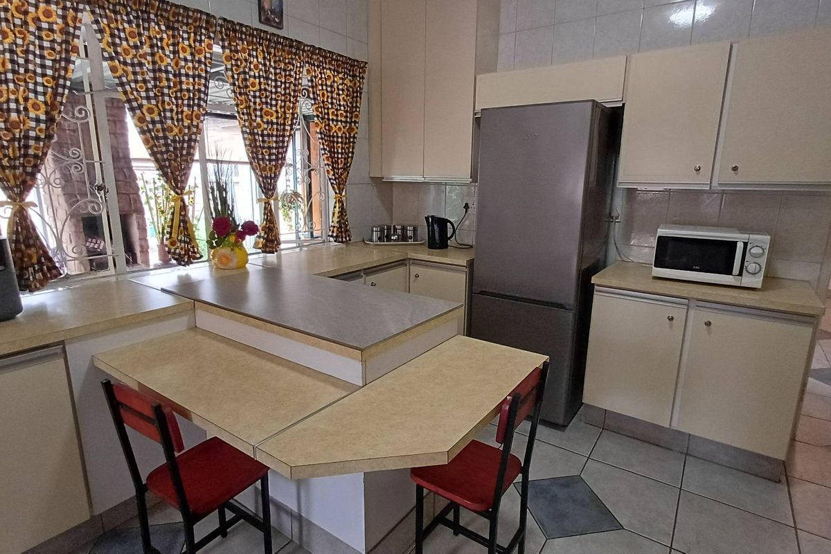 Functional kitchen featuring laminate countertops, built-in cabinetry, tiled flooring, and a breakfast nook area with direct access to the outdoor space.