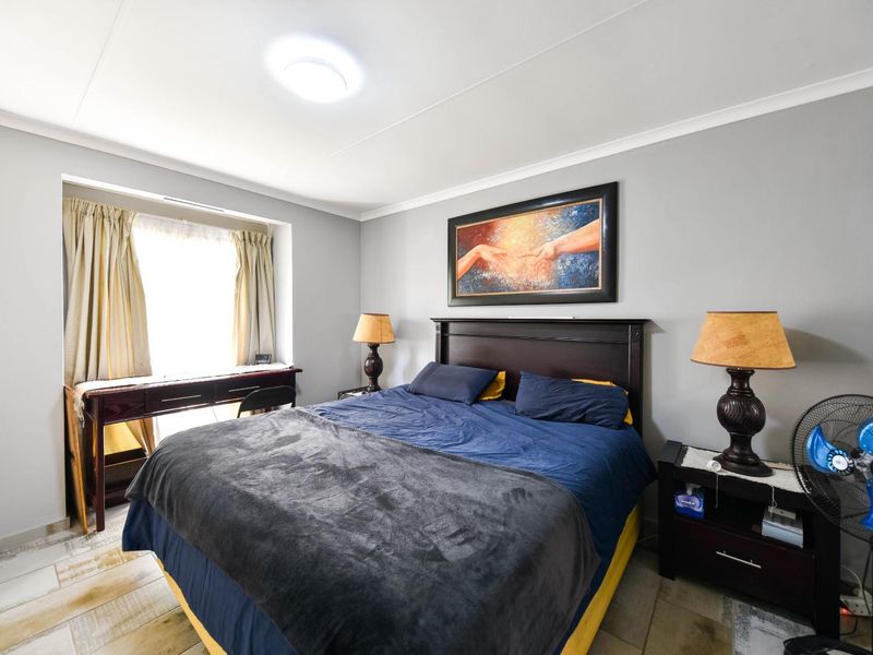 A well-lit bedroom featuring tiled flooring, neutral wall finishes, and a classic cove cornice detail.
