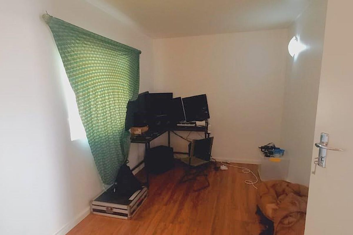 A functional bedroom or office space featuring wood-look flooring and a wall-mounted light fixture.