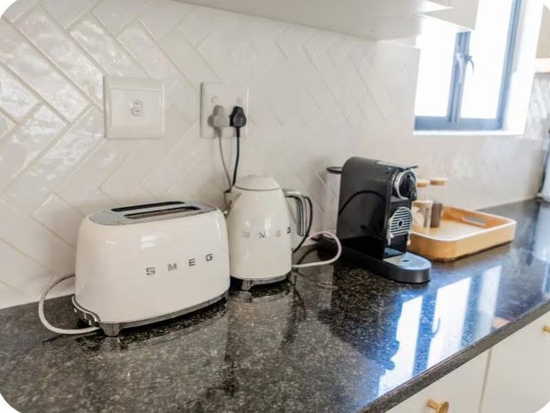 A modern kitchen featuring a polished granite countertop and a stylish white herringbone tile backsplash with integrated electrical outlets.