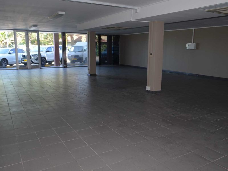Spacious open-plan garage area featuring tiled flooring, structural support columns, and large glass sliding doors providing natural light and exterior access.