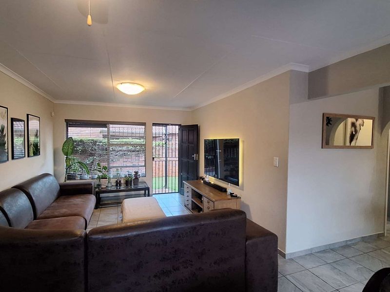 A comfortable living room featuring tiled flooring, a security gate leading to the exterior, and an arched entryway connecting to the rest of the home.