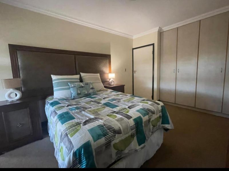 A bedroom featuring neutral walls, crown molding, carpeted flooring, and ample built-in cupboard storage.