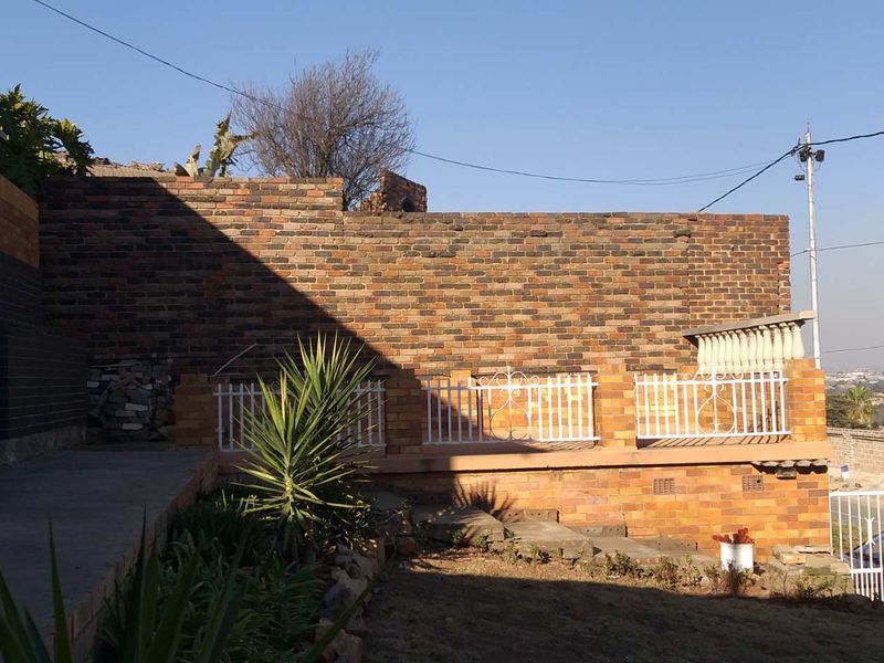 Rear exterior area featuring a face brick retaining wall, concrete paving, and decorative wrought iron balustrades.