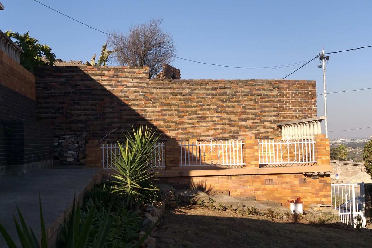 Rear exterior area featuring a face brick retaining wall, concrete paving, and decorative wrought iron balustrades.