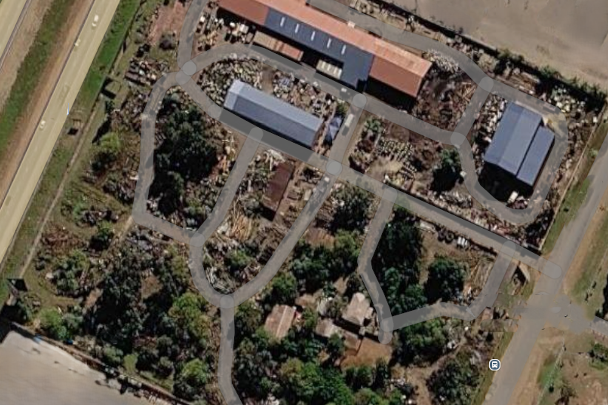 Aerial view of an industrial property featuring multiple warehouse structures, paved access roads, and surrounding yard space.