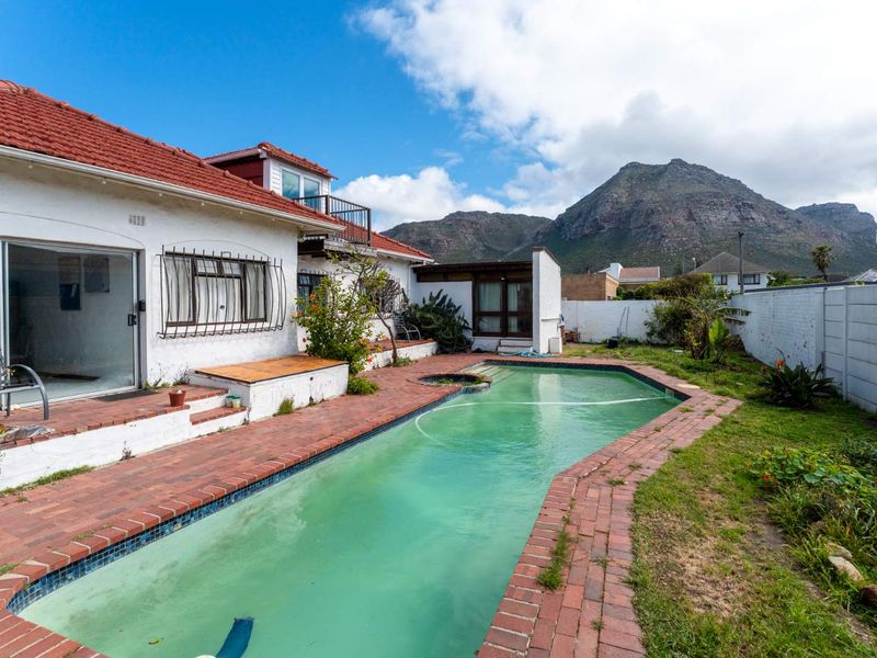 Rear exterior view featuring a swimming pool, brick patio area, and mountain views, showing potential for outdoor landscaping and pool maintenance.