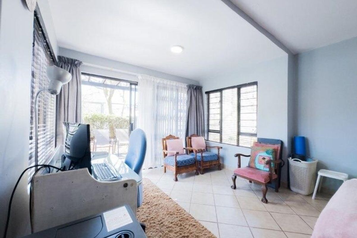 A bright living area featuring tiled flooring, large windows, and a sliding glass door providing access to the outdoor space.