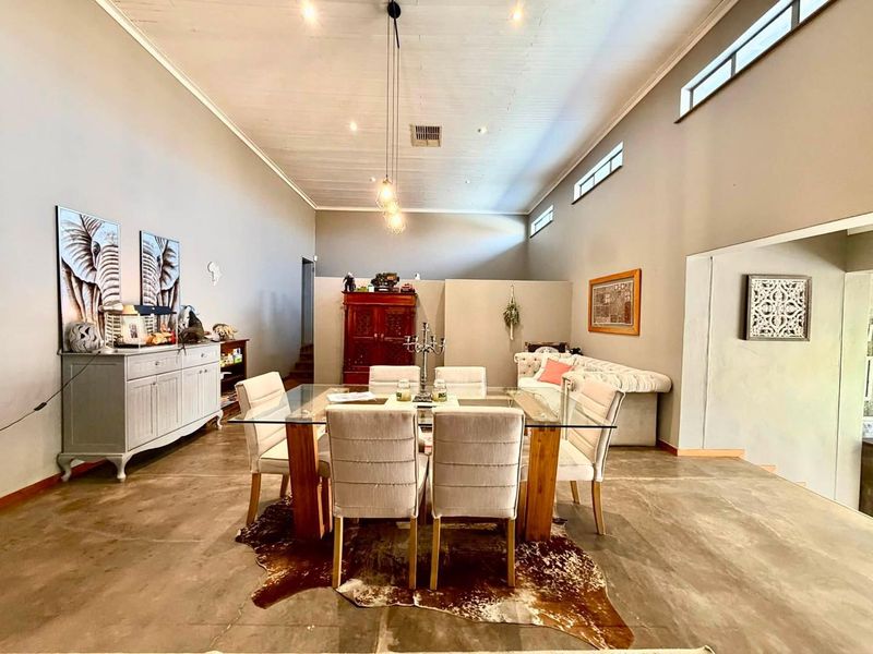 Spacious dining area featuring polished concrete floors, high vaulted ceilings with clerestory windows, and modern pendant lighting, creating an open and airy atmosphere.