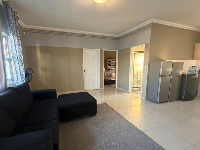 Open plan living area featuring tiled flooring, decorative ceiling cornices, and direct access to adjacent bedroom and bathroom spaces.