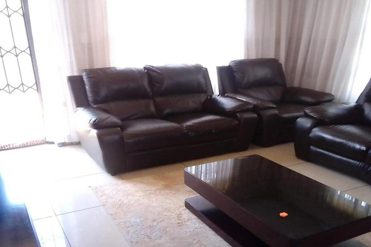 A living room featuring tiled flooring and a security gate leading to an outdoor area, providing a functional and bright living space.