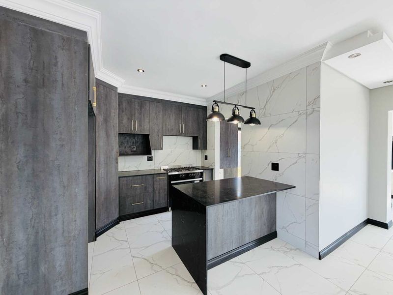 Modern kitchen featuring dark textured cabinetry, a central island, gas hob, marble-look wall tiles, and high-quality porcelain flooring with recessed and pendant lighting.