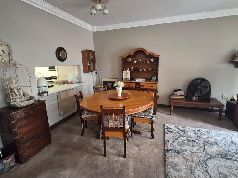 Open plan living and dining area featuring a serving hatch connecting to the kitchen and decorative crown molding.
