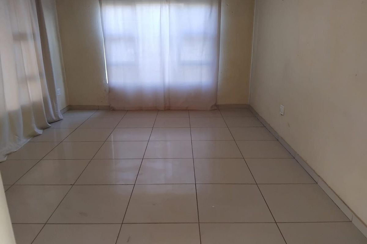 An empty living room featuring neutral ceramic floor tiles and plain walls, providing a blank canvas for interior design and personalization.