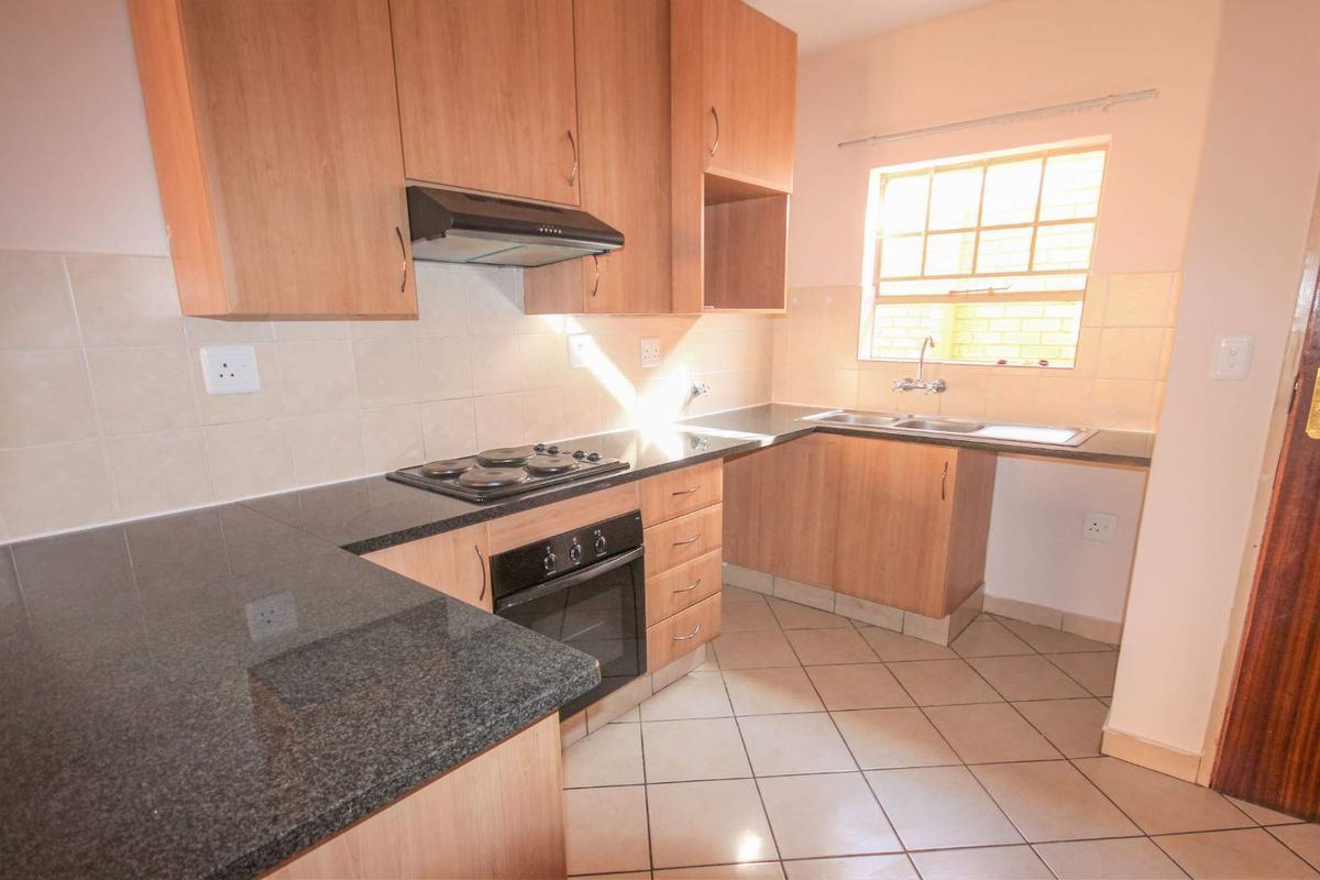 A functional kitchen featuring laminate cabinetry, granite countertops, built-in oven, electric hob, extractor fan, and a double sink with tiled backsplash.