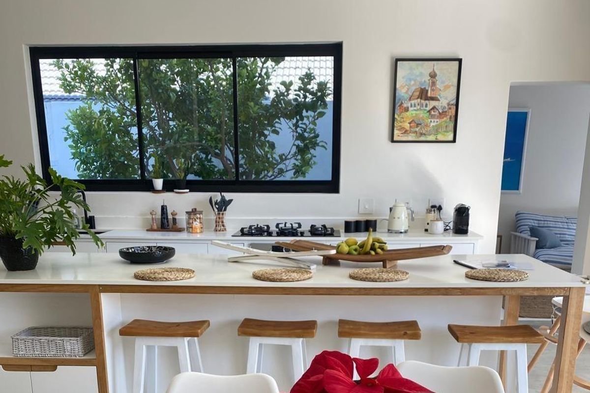 Modern kitchen featuring a central island with breakfast bar seating, integrated gas cooktop, and a large window overlooking the garden.