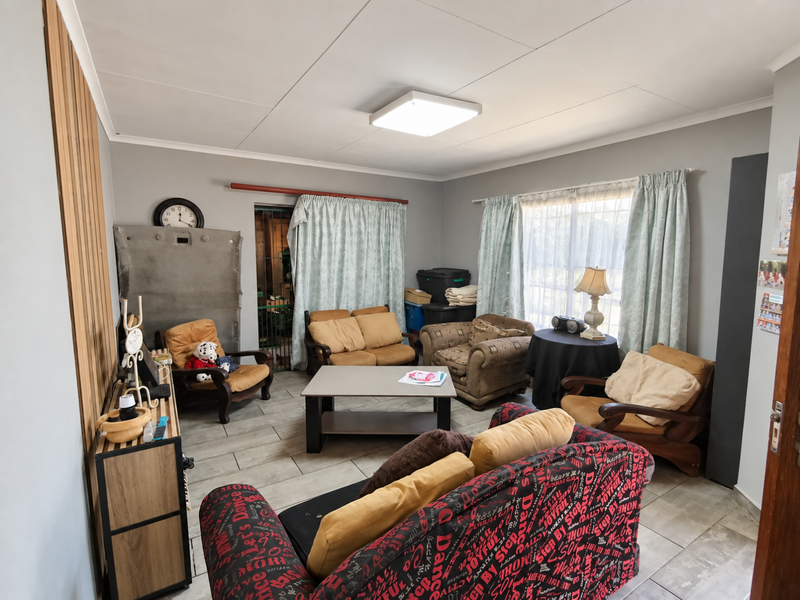 A living room featuring tiled flooring, slat wall paneling, and natural light through large windows.