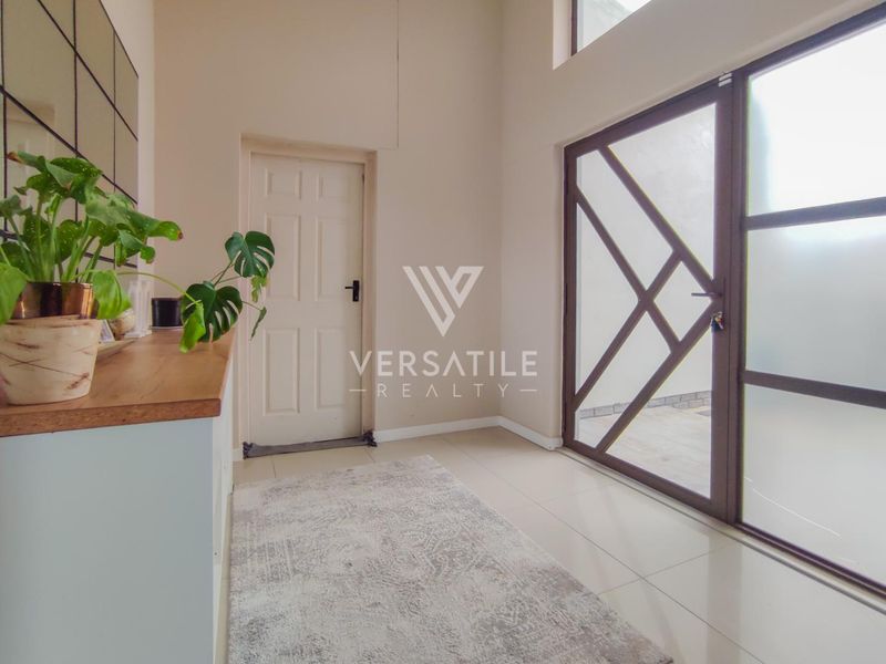 Bright entrance hall featuring high ceilings, tiled flooring, and a large glass-panelled door providing natural light.