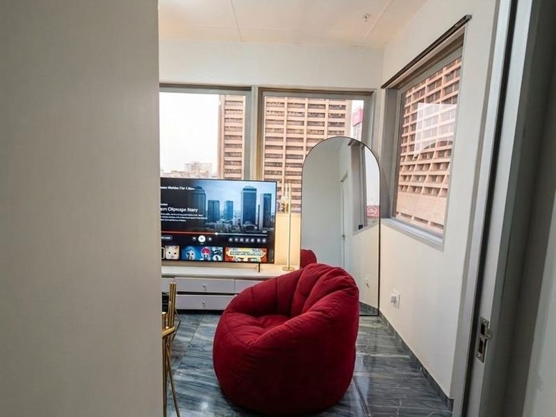 A compact living area featuring large windows with city views, tiled flooring, and a drop ceiling.