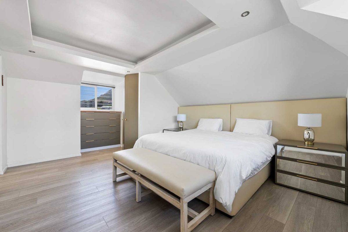 A spacious bedroom featuring a sloped ceiling, recessed lighting, laminate flooring, and a built-in cupboard.